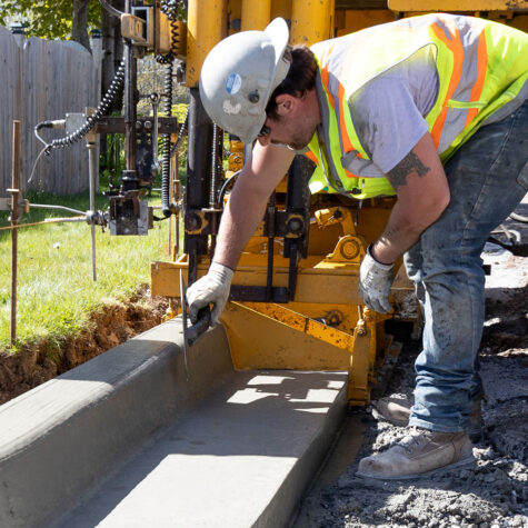 A worker of United Concrete & Asphalt taking pride in smoothing the curb off a road.